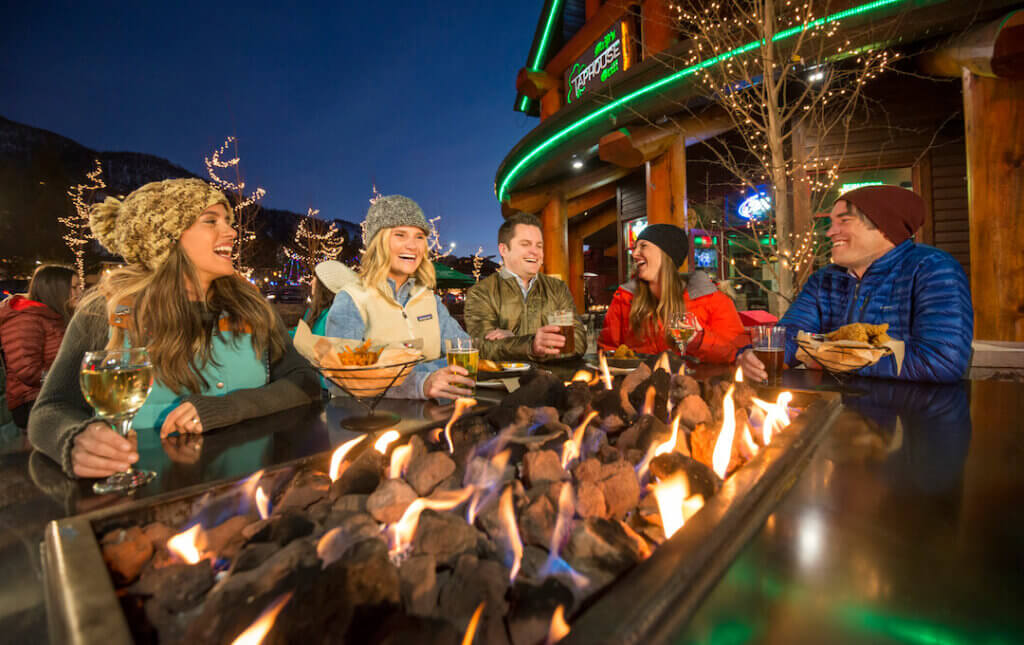 Friends enjoying apres drinks by a fire pit at Heavenly Village
